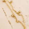 Gold chain necklace with small diamond-like stones on a beige marble surface