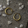 Gold hoop earrings on a textured surface with small stones
