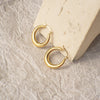 Gold hoop earrings on a textured stone surface