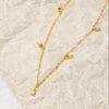 Gold necklace and earrings on a beige marble surface