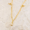 Gold necklace with pearl pendants on a beige marble background