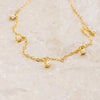 Gold necklace with pearl charms on a light beige background