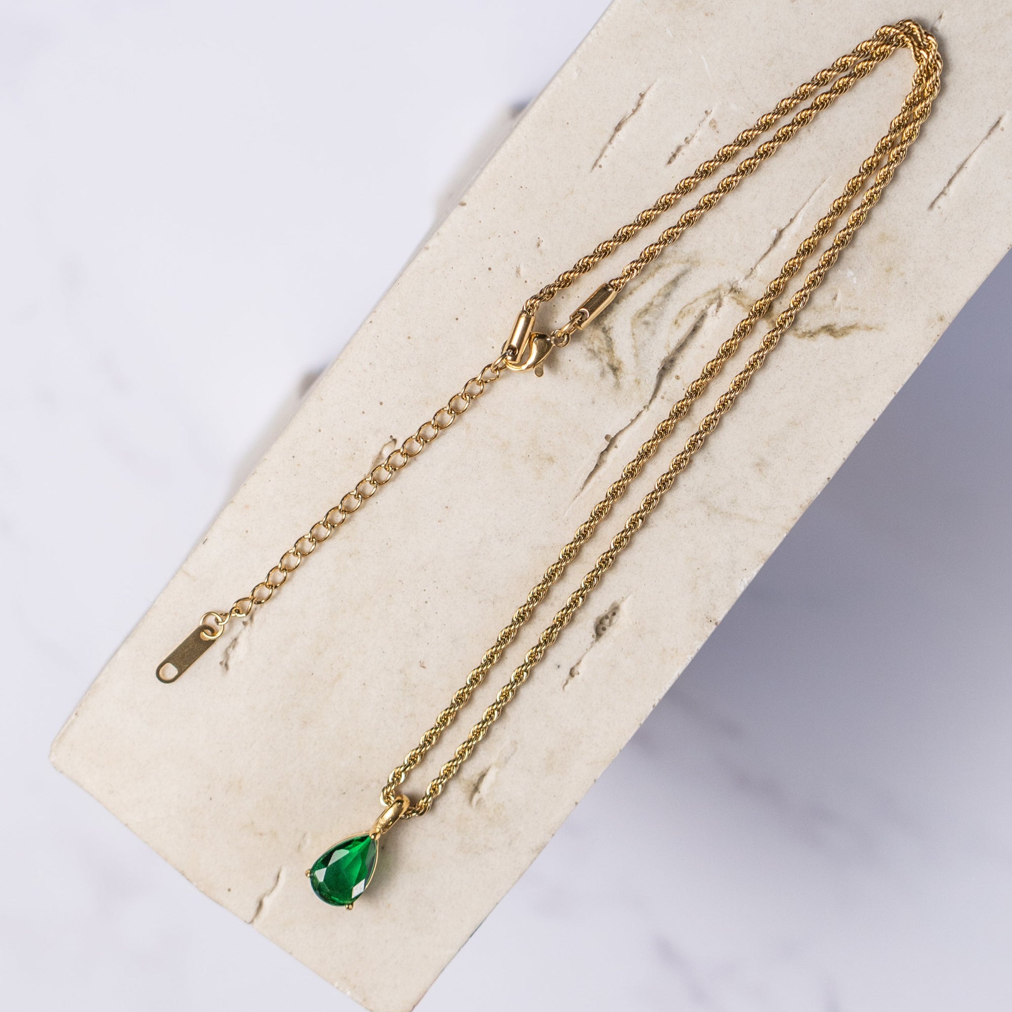 A gold necklace with an emerald zirconia pendant