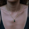 A model wearing a gold necklace with emerald zirconia pendant.
