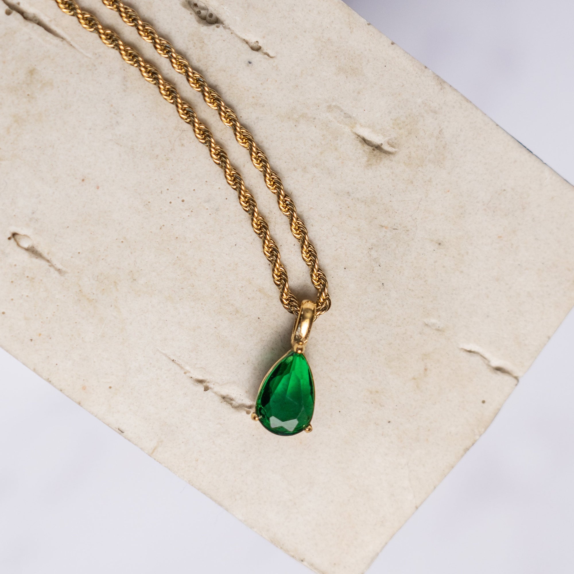 A gold necklace with an emerald zirconia pendant