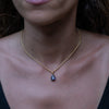 A woman wearing a gold necklace with sapphire zirconia