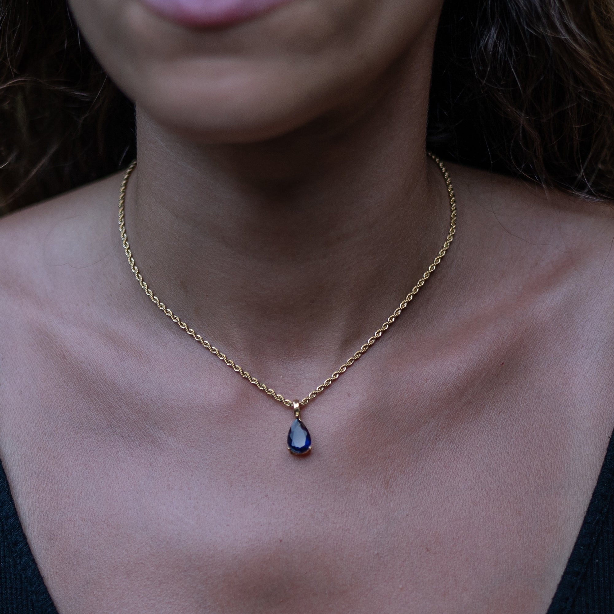 A woman wearing a gold necklace with sapphire zirconia