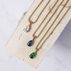 Three gold necklaces with three different pendant colors: clear, sapphire, and emerald.