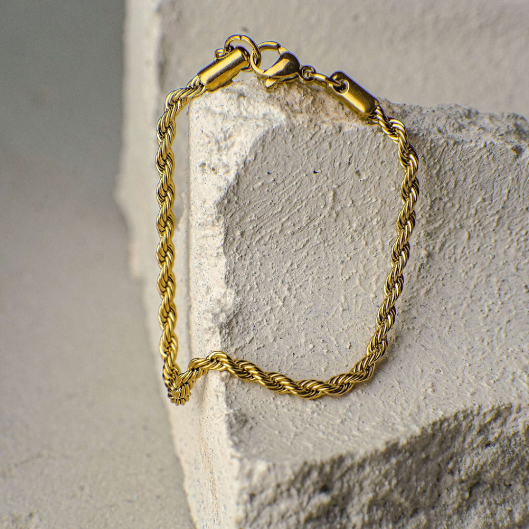 Gold rope chain bracelet on a textured stone surface