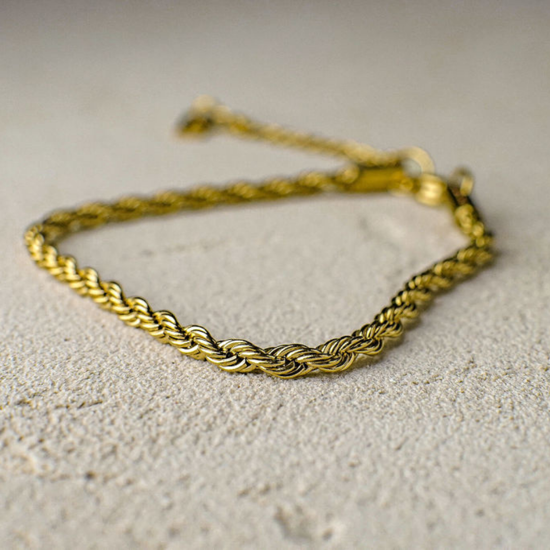 Gold braided bracelet on a textured beige surface