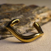 Gold curvy bangle on a textured surface
