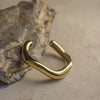 Gold curvy bangle on a textured stone surface