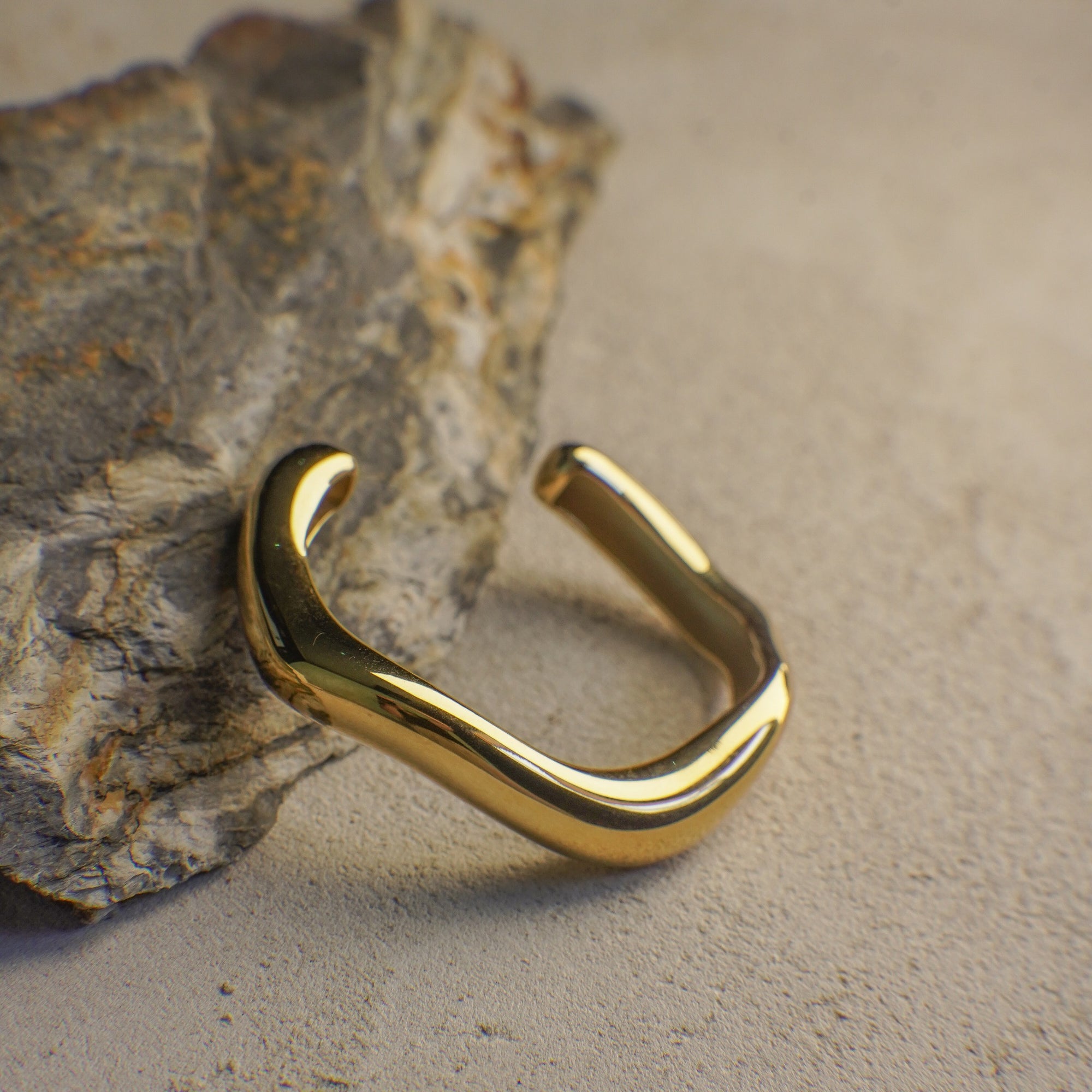 Gold curvy bangle on a textured stone surface
