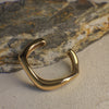 Gold curvy bangle on a textured stone surface