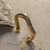Gold curvy bangle on a textured stone surface