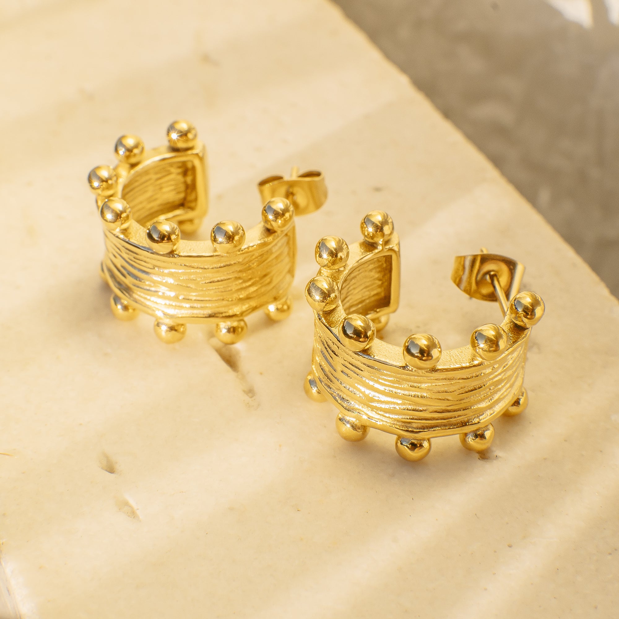 Gold hoop earrings on a beige surface