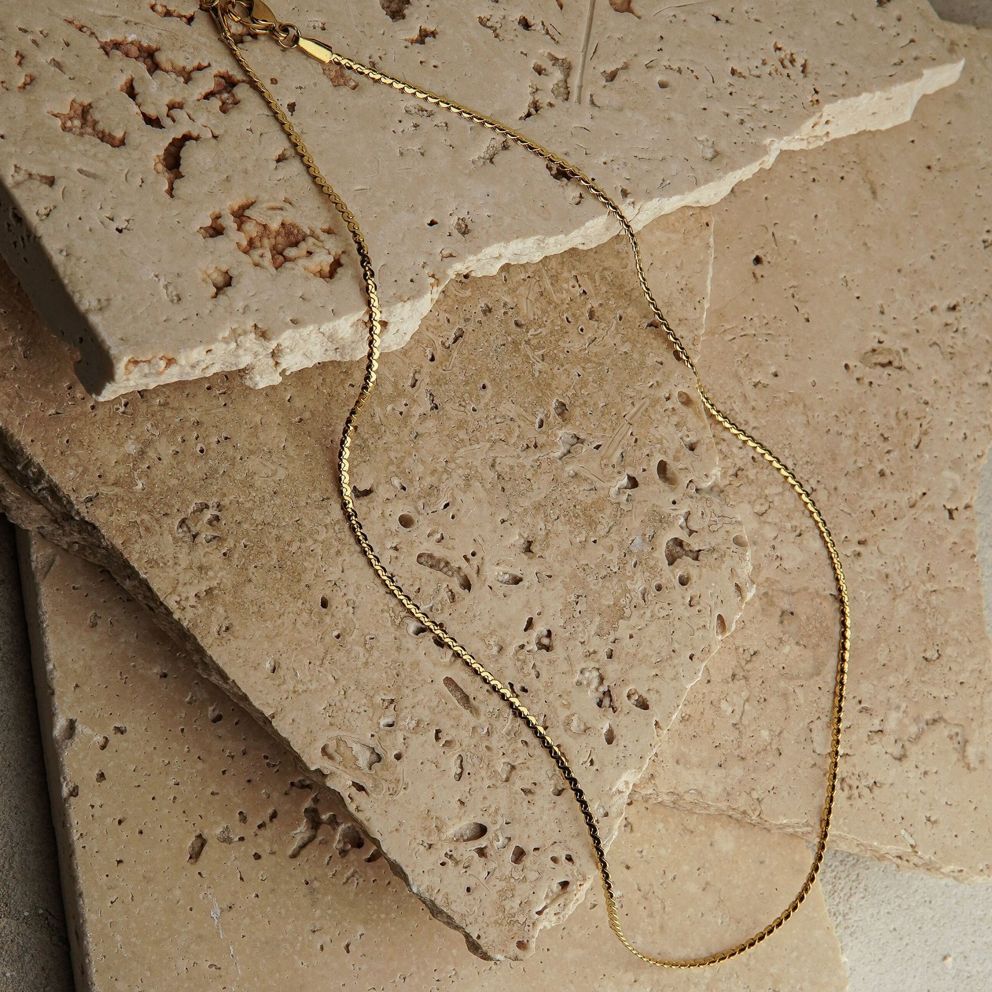 Gold necklace on a textured stone surface