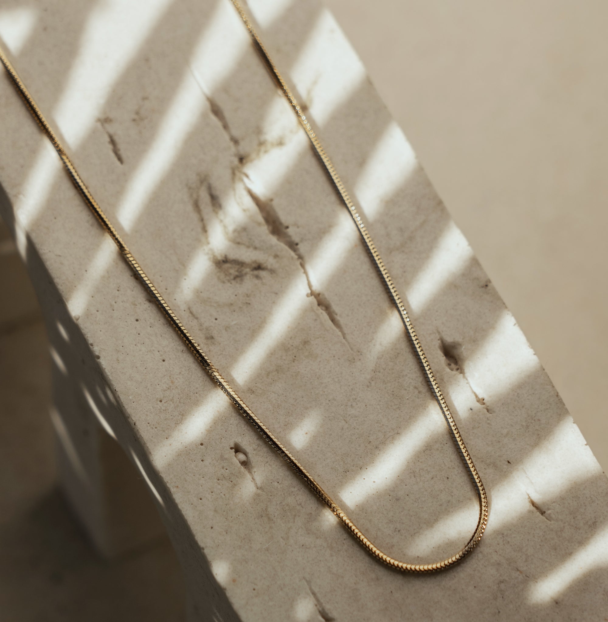 A classic gold necklace on a textured surface