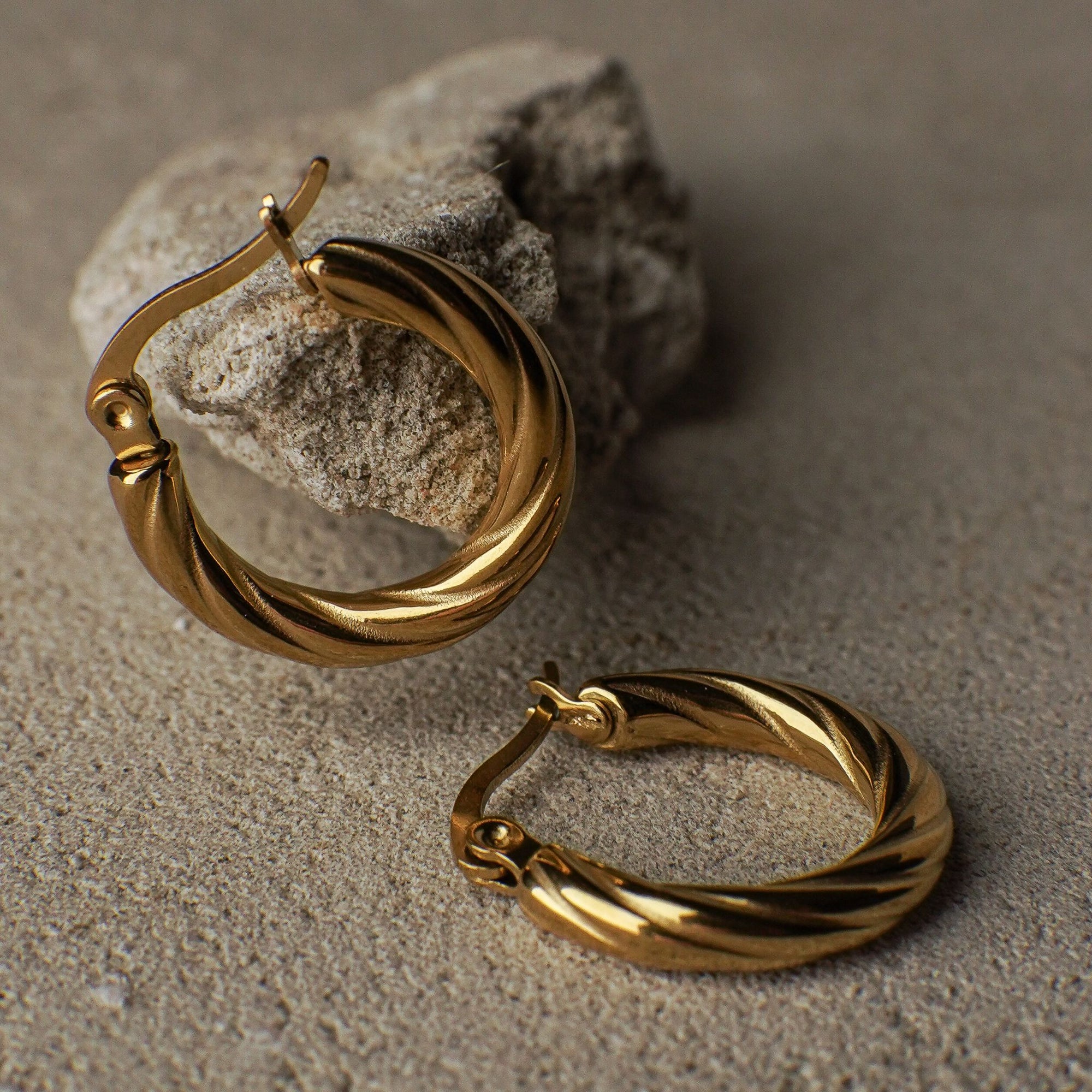 Pair of gold hoop earrings on a textured surface