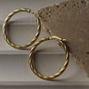 Gold hoop earrings on a textured stone surface