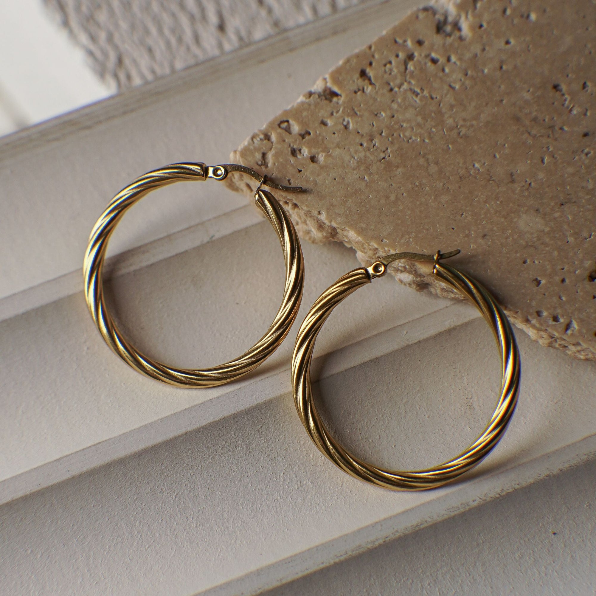 Gold hoop earrings on a textured surface