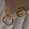 Gold hoop earrings on a stone surface