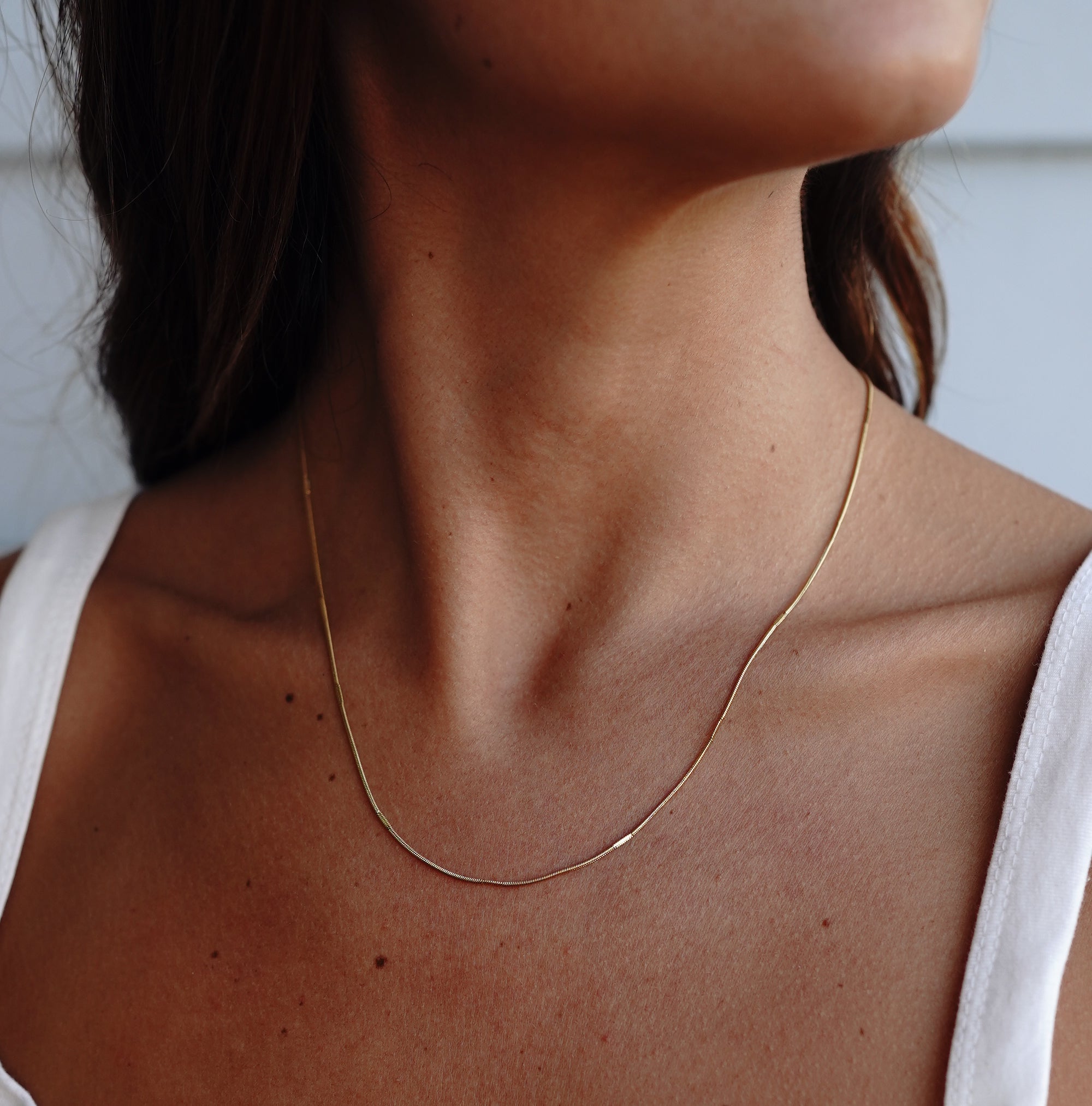 A model wearing a thin gold necklace