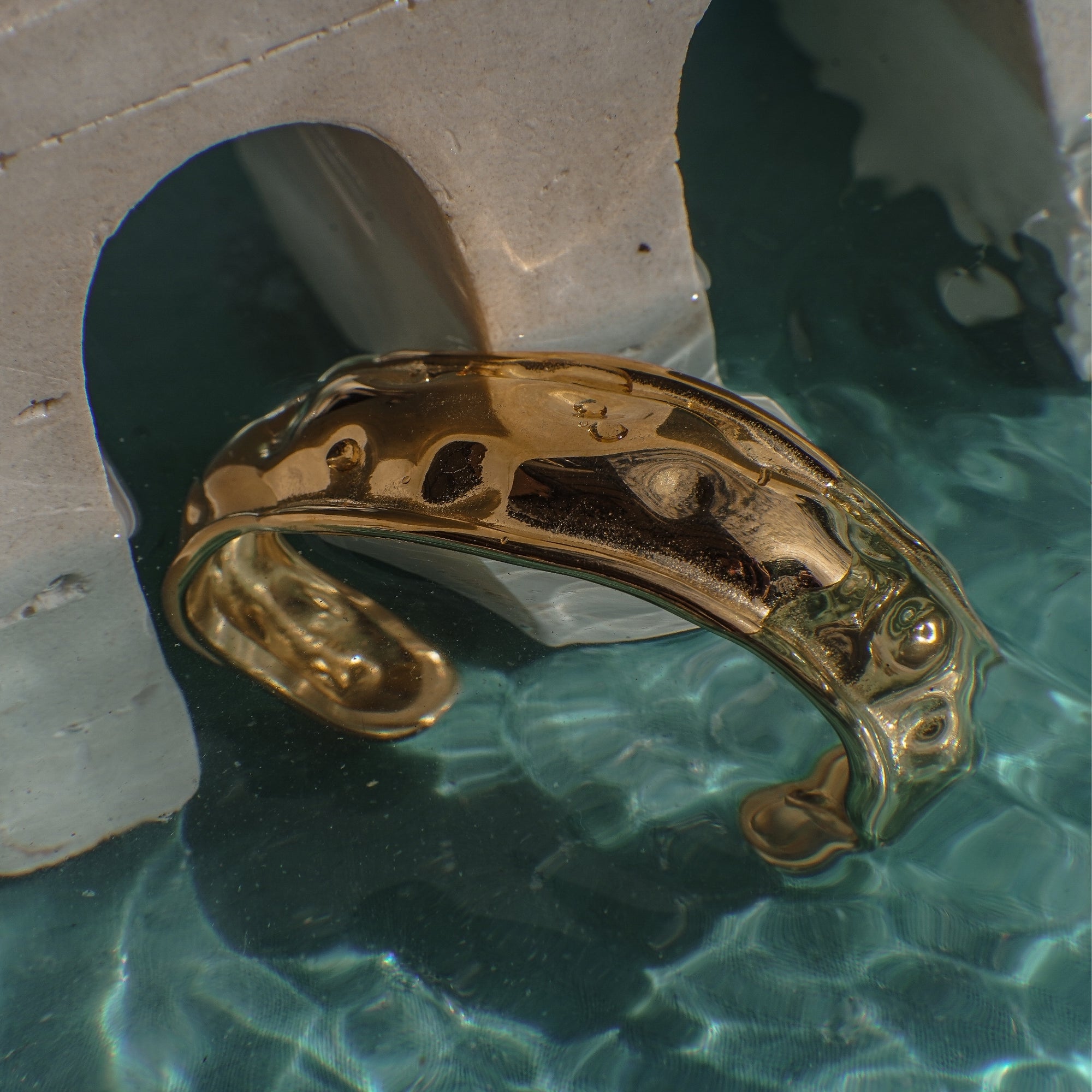 Gold ring on a stone surface with water reflection