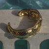 Gold bracelet on a stone surface with a pool in the background