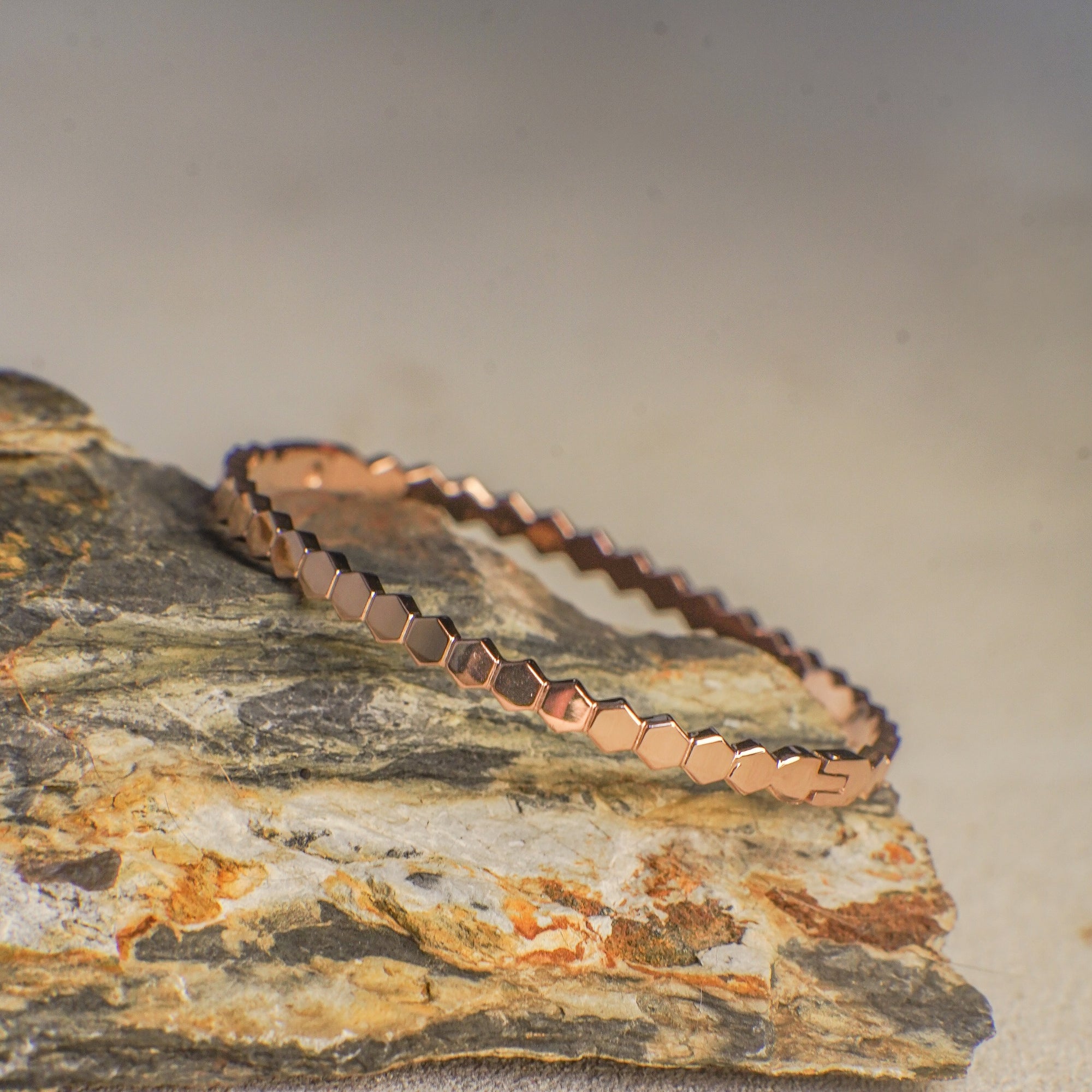 Rose gold bracelet on a textured stone surface