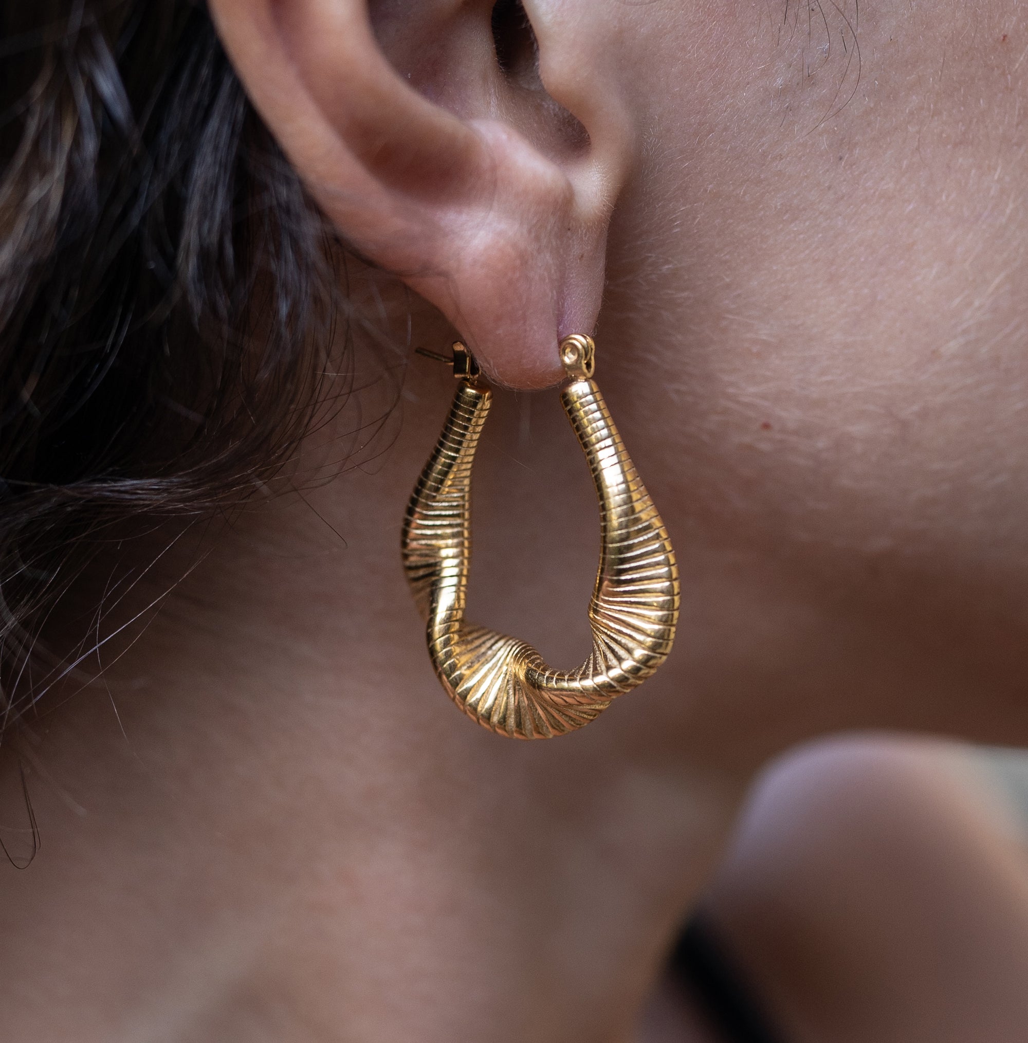 A woman wearing Nina Gold Drop Earrings on her right ear