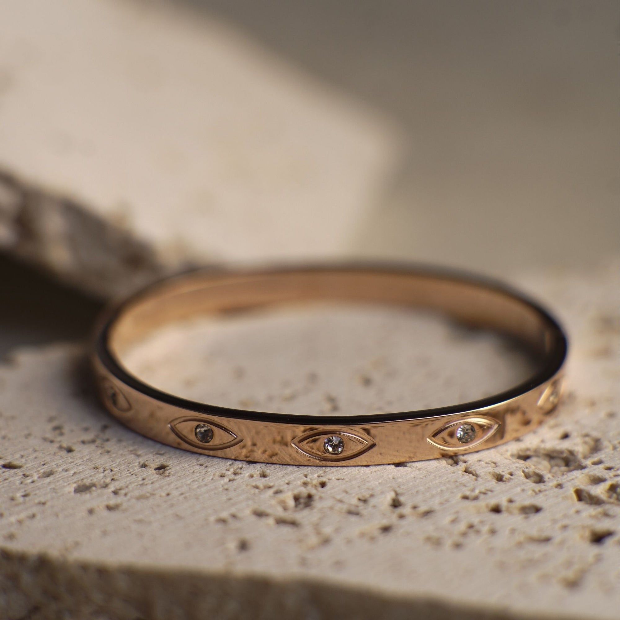 Bronze bracelet with eye designs on a stone surface