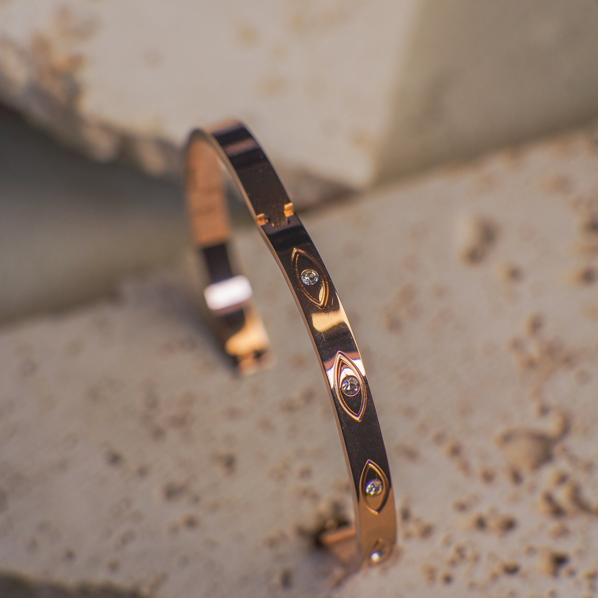 Rose gold bracelet with diamond accents on a textured surface