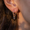 A rose gold earring with an Emerald drop pendant on a model's ear.