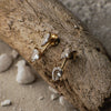 Gold earrings with clear stones on a textured stone surface
