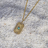 Gold necklace with a pendant featuring a turquoise stone on a textured surface