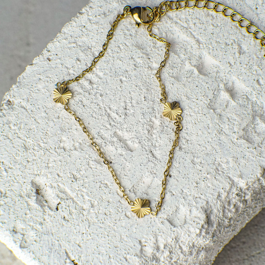 Gold bracelet with star-shaped charms on a textured stone surface