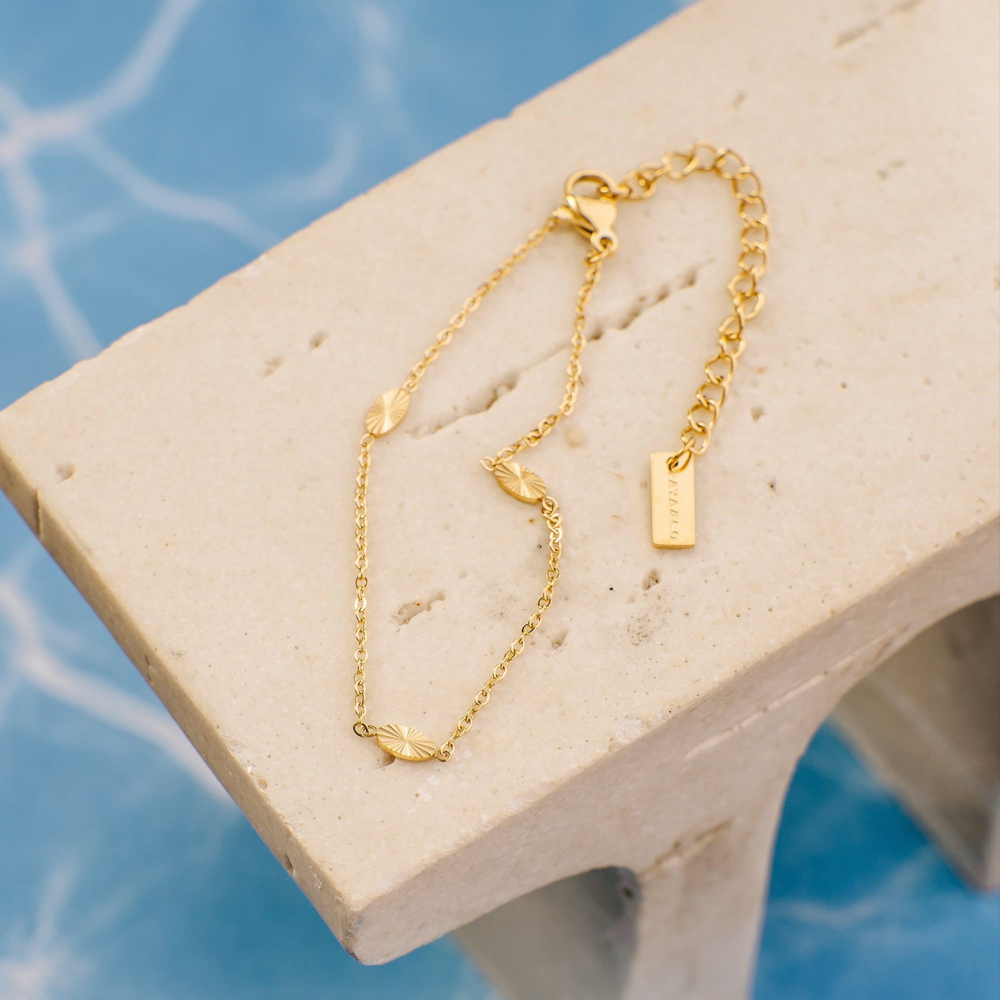 Gold bracelet on a stone surface with a blue marble background