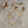 Gold bracelet with square pendants on a sandy surface