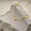 Gold bracelet with sunflower-shaped charms on a textured stone surface
