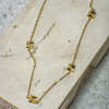 Gold necklace with geometric pendants on a textured surface