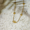 Gold necklace with geometric pendants on a textured white surface