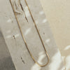 A gold necklace laid out on a flat surface, displaying a twisted chain design.