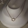 Gold necklace with a circular pendant on a mannequin bust.