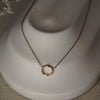 Gold necklace with a circular pendant on a mannequin bust.