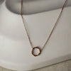 Gold necklace with a circular pendant on a white surface