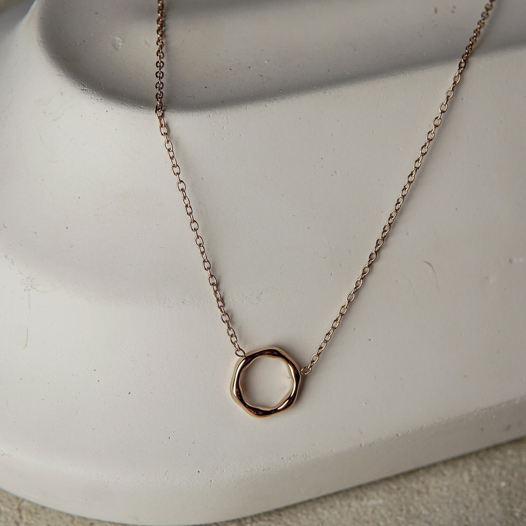 Gold necklace with a circular pendant on a white surface
