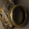 Gold ring with textured design on a stone surface