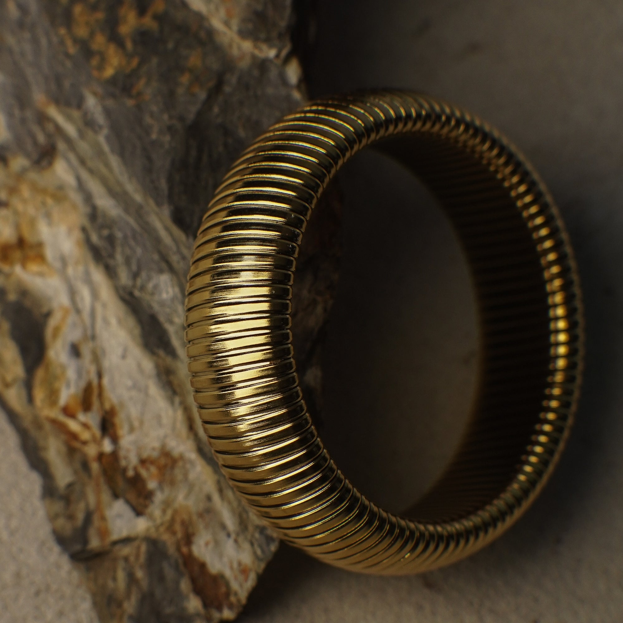 Gold ring with textured design on a stone surface