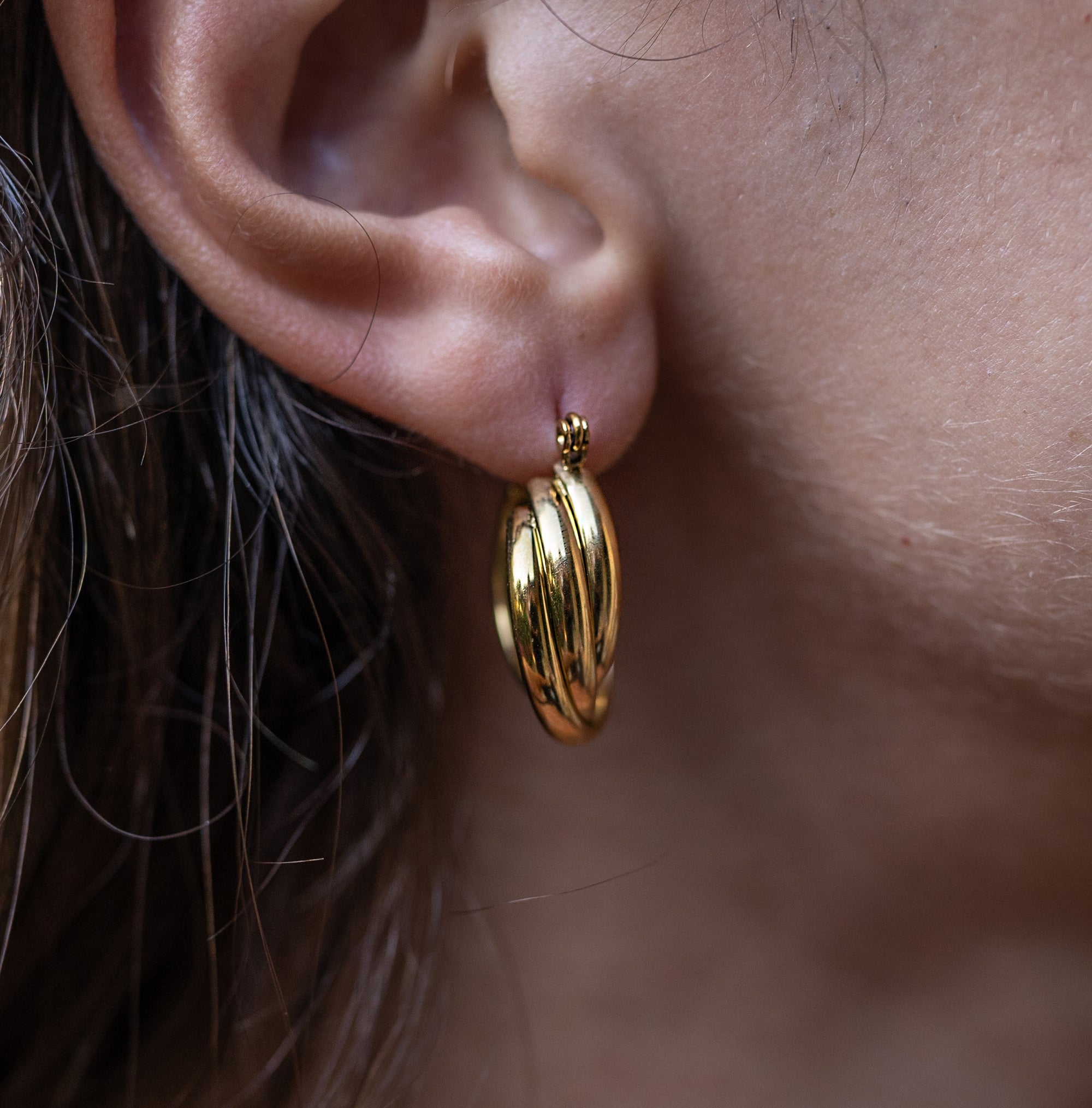 A woman wearing the Ottilie Gold Hoop Earrings on her right ear